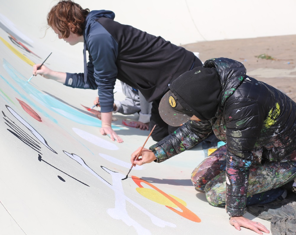 2 youth boys painting the walls of a skatepark ramp