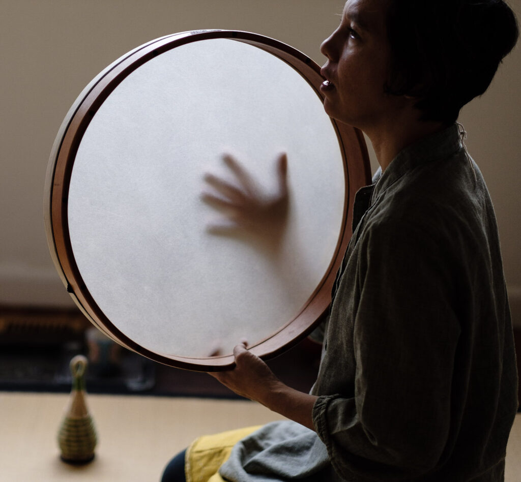 Ria Soemardjo frame with drum in hand. 